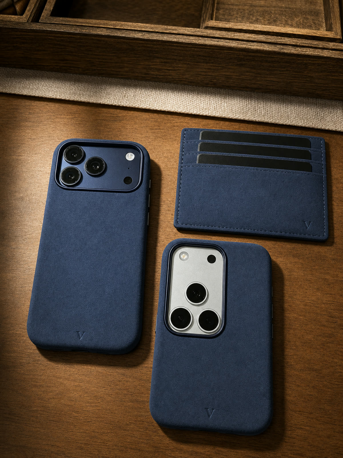 Two navy Virela iPhone 17 cases and cardholder on warm wood