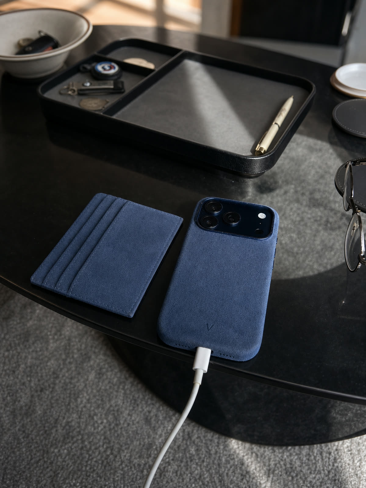 Navy Virela iPhone 17 case and matching cardholder in a refined desk setting