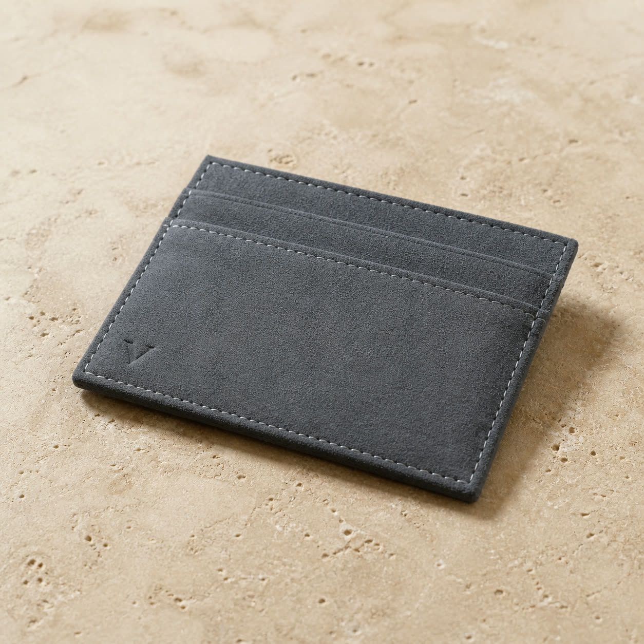 Graphite Virela cardholder rotated with its physical bottom at image-left and engraved V at physical bottom-right