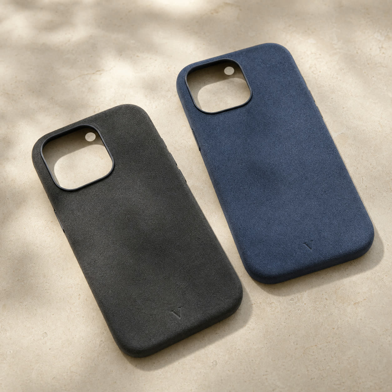 Graphite and navy Virela phone cases with subtle lower-center engraved V marks